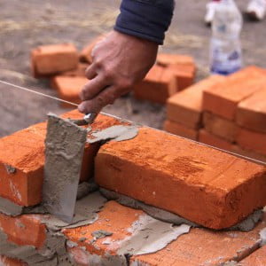 поправляем мастерком кирпич при кладке